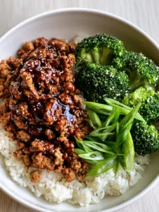 Close-up of browned crumbled turkey in a dark glossy honey garlic sauce next to vibrant green broccoli and white rice. (Honey Garlic Ground Turkey Skillet)