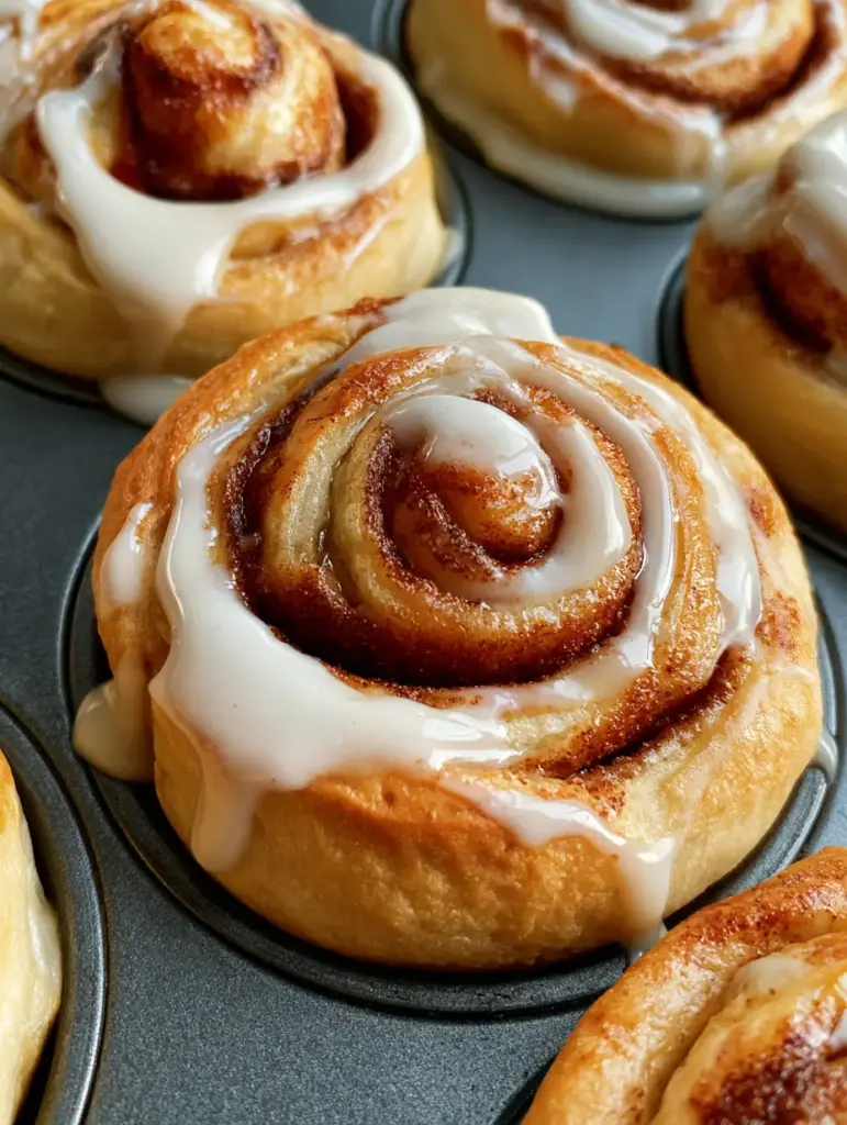 A top-down view of Cinnamon Roll Muffins in a dark grey tin with generous white icing pooling in the center.